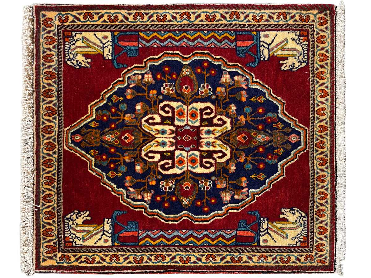 Rectangular rug with a red background, dark blue ornaments, and beige decorative borders