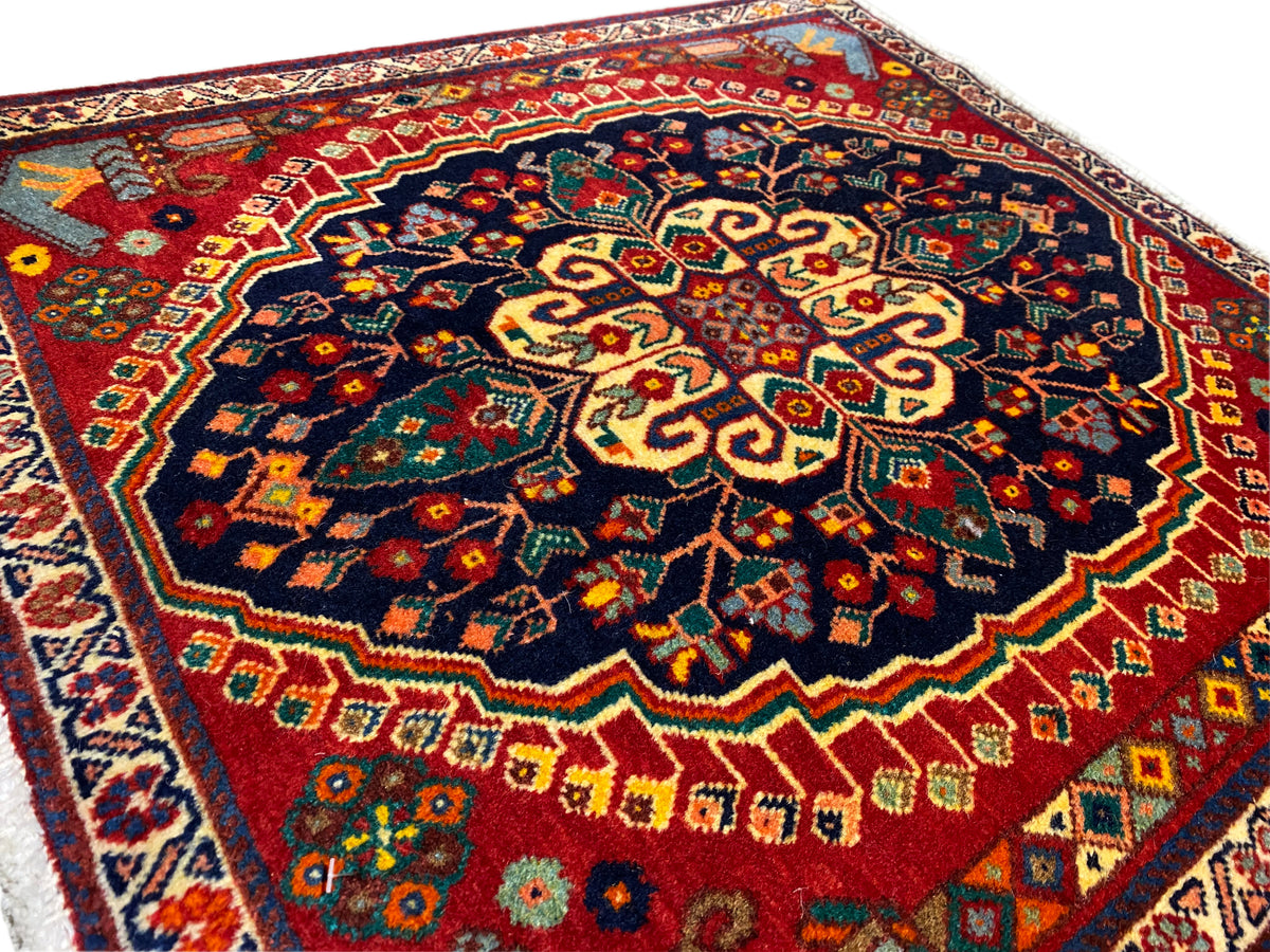 Carpet detail from the corner: dense pattern in dark blue, red, yellow, and green