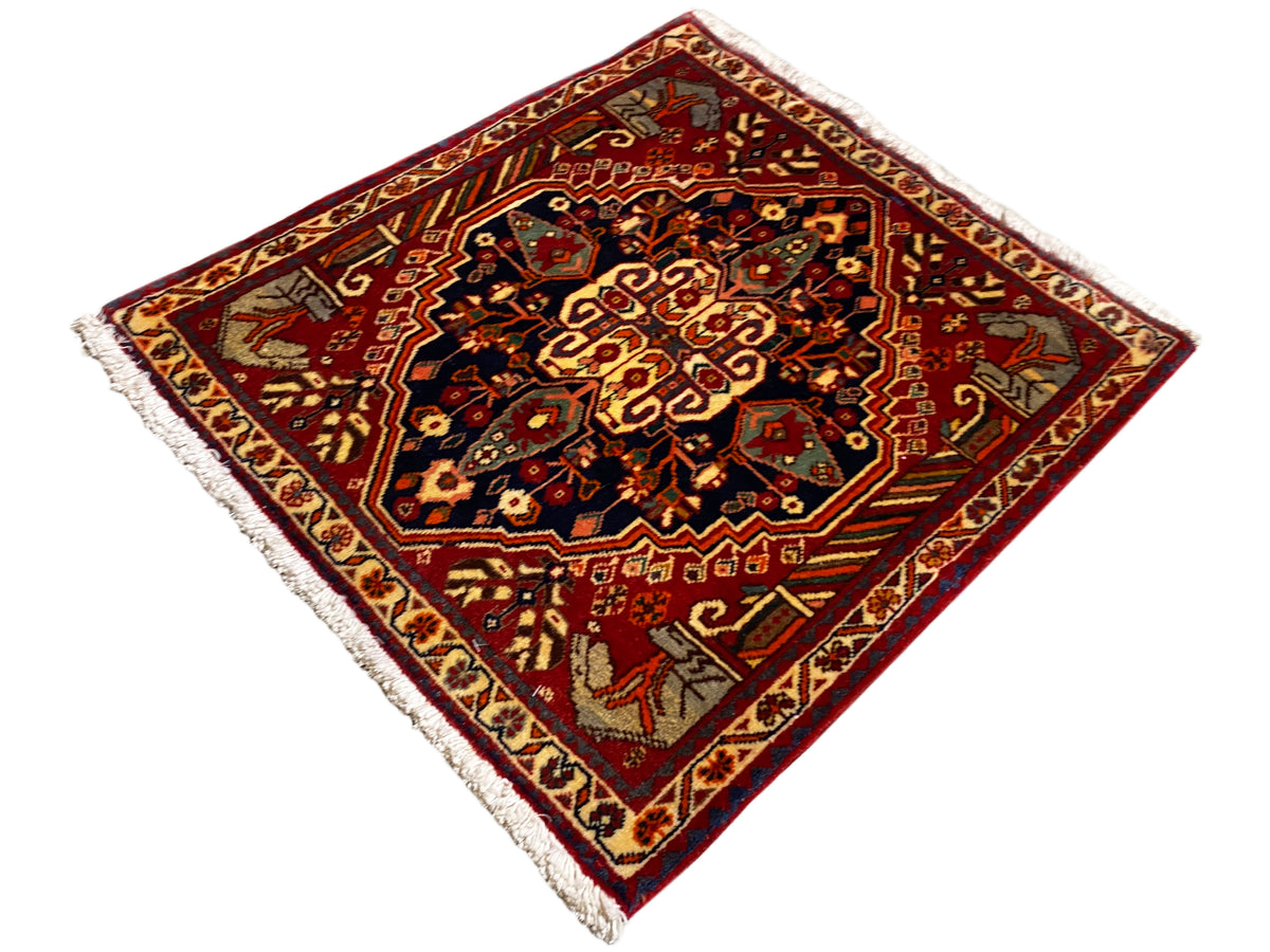 Rug 65x59 cm with a red background, dark central ornaments, and fringes along the edges
