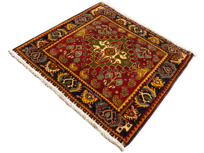 Rug corner with a red pattern, green accents, a dark border, and fringe