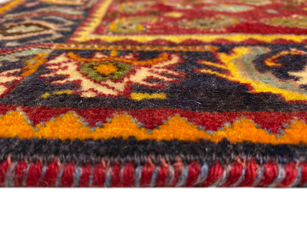 Rug edge with fringes and a patterned border in red, orange, blue, and black