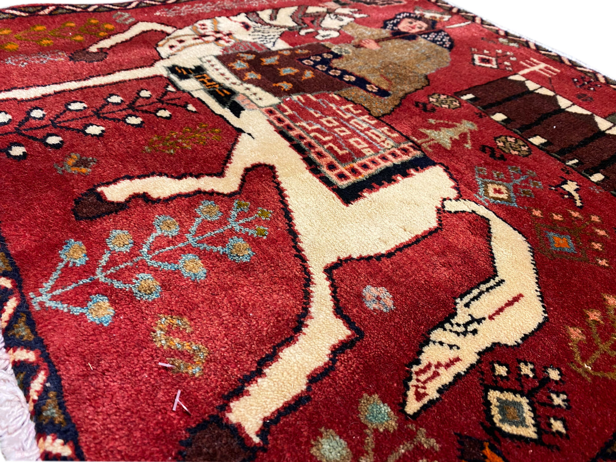 Close-up of a Poshti carpet with a red background, horses and a depiction of a woman, colorful patterns