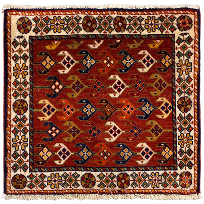Square rug with a red background, a colorful white border, and fringes
