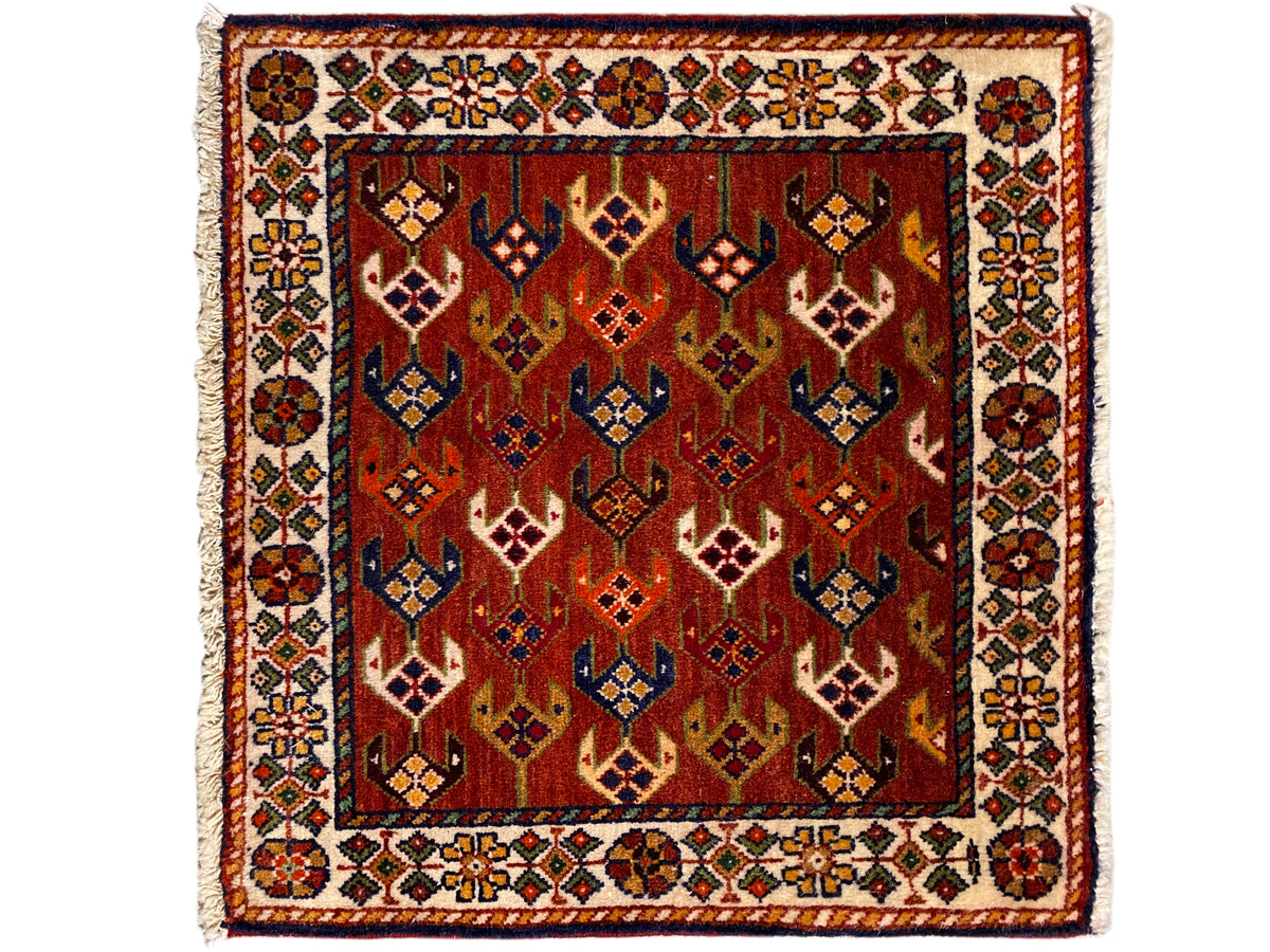 Square rug 61x61 cm with a red patterned field, ornamental border, and fringes