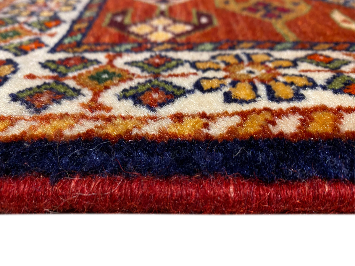 Carpet edge with red pile, a dark border, and an ornamental patterned stripe