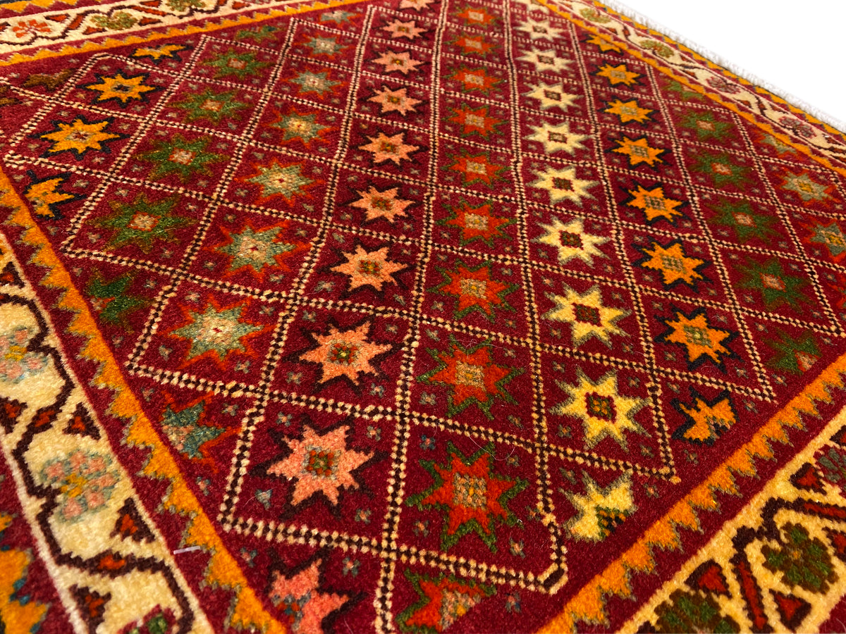 Poshti rug close-up: an intensely colored star and diamond pattern in the rug field.