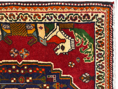 Close-up of a Poshti rug, red field with animals, blue decorative edge and patterned border