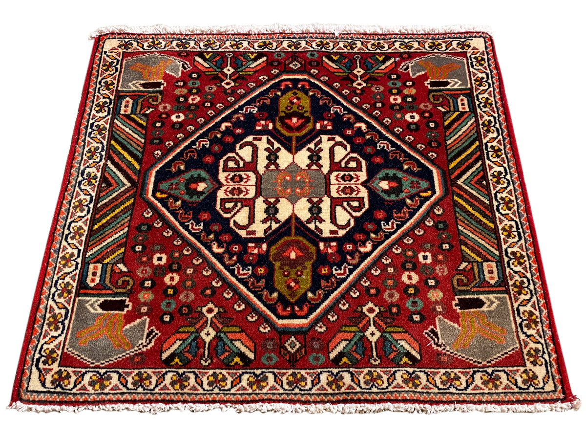 Rectangular Oriental rug with a red pattern, blue inner border, and edge ornaments