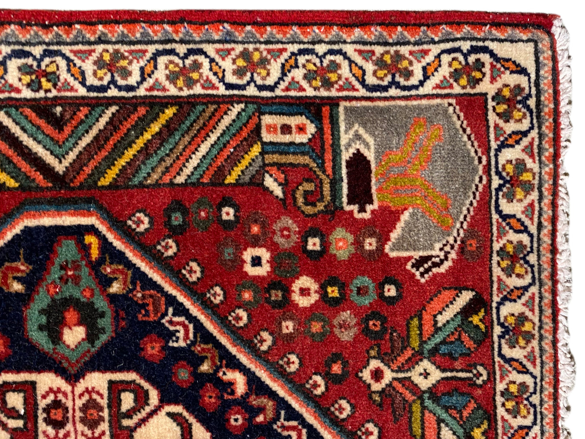 Detailed view: red carpet with ornamental motifs, multicolored border, and fringes
