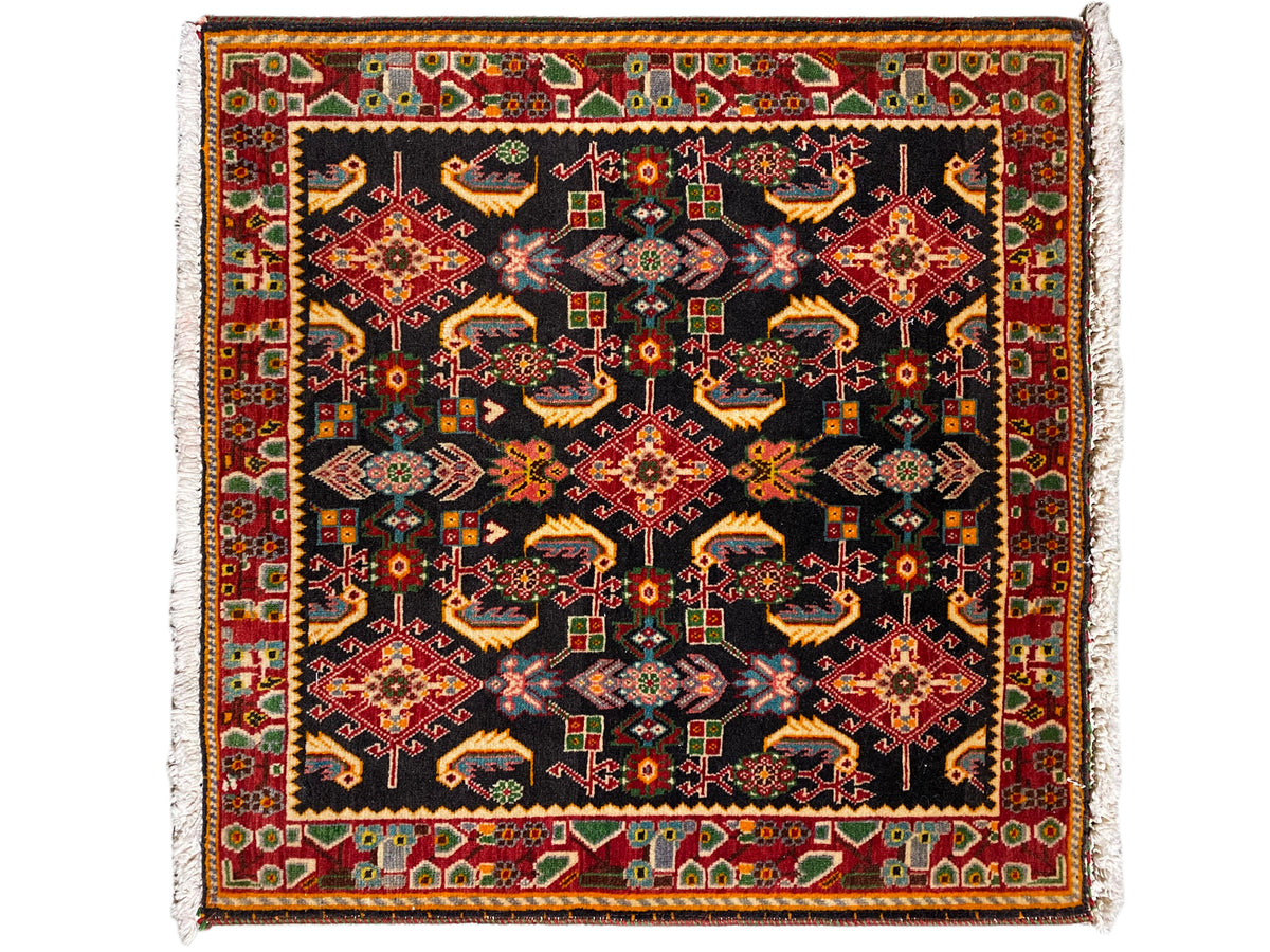 Rug with a square ornamental pattern, black as the base, with shades of red, yellow, and green