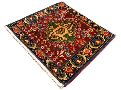 Rectangular rug (67x66 cm) with a red center, dark border, multicolored ornaments, and fringe
