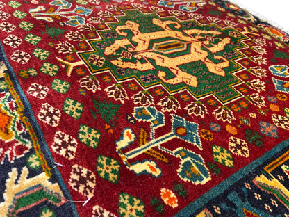 Carpet front detail with a red field, star-shaped patterns, and turquoise lines, textured pile