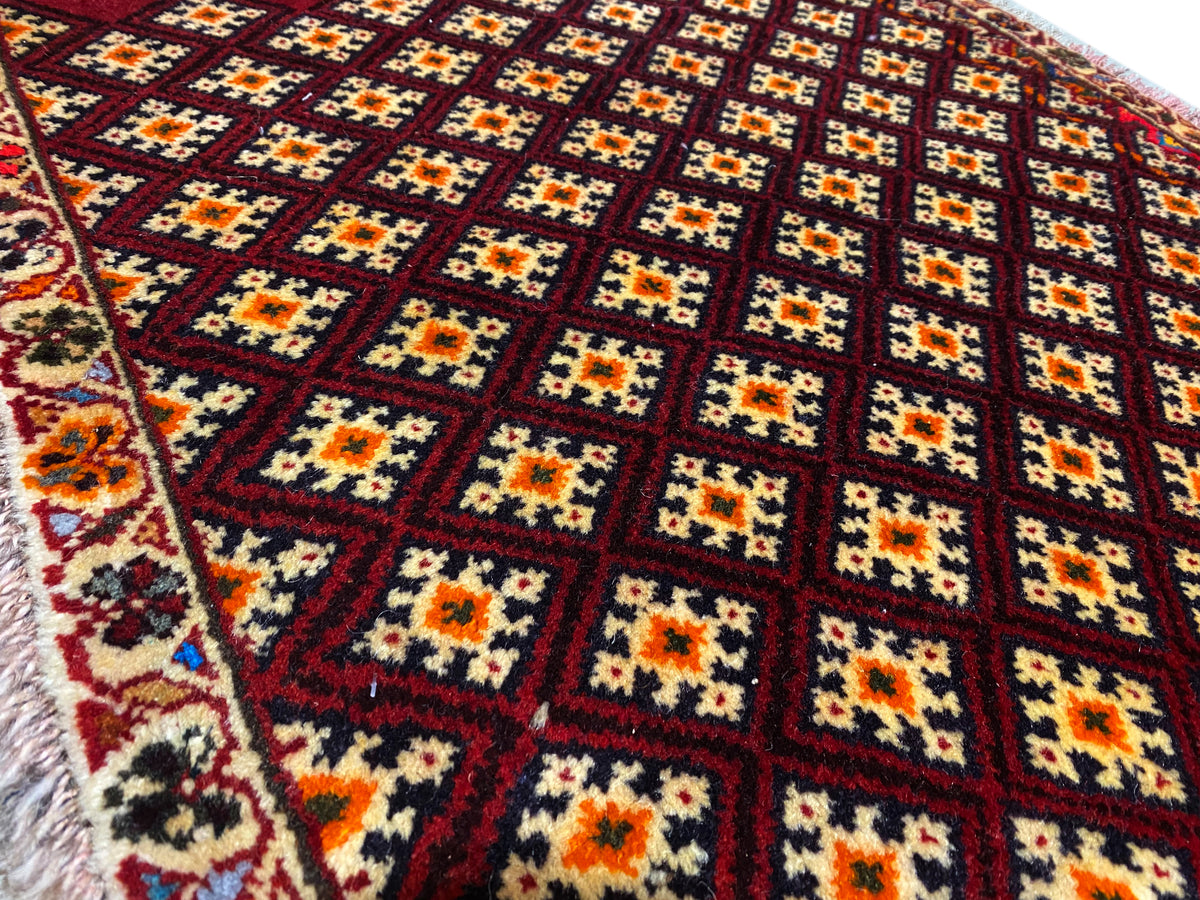 Poshti rug 61x59 cm: close-up of the pattern with colorful diamonds on a dark red background