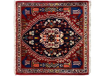 Rectangular rug with a red border, dark blue inner field, and geometric pattern
