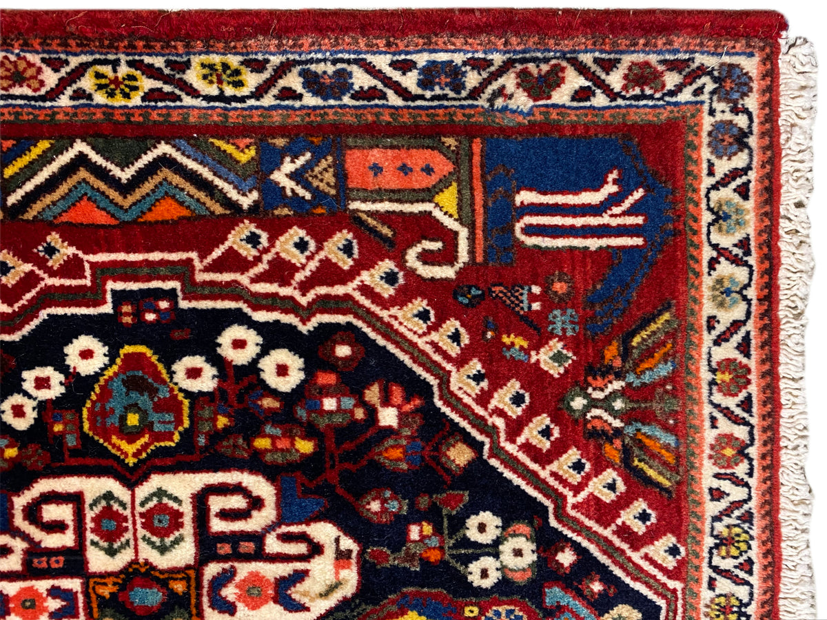 Detailed view of the rug: red background, dark blue field, ornaments and border