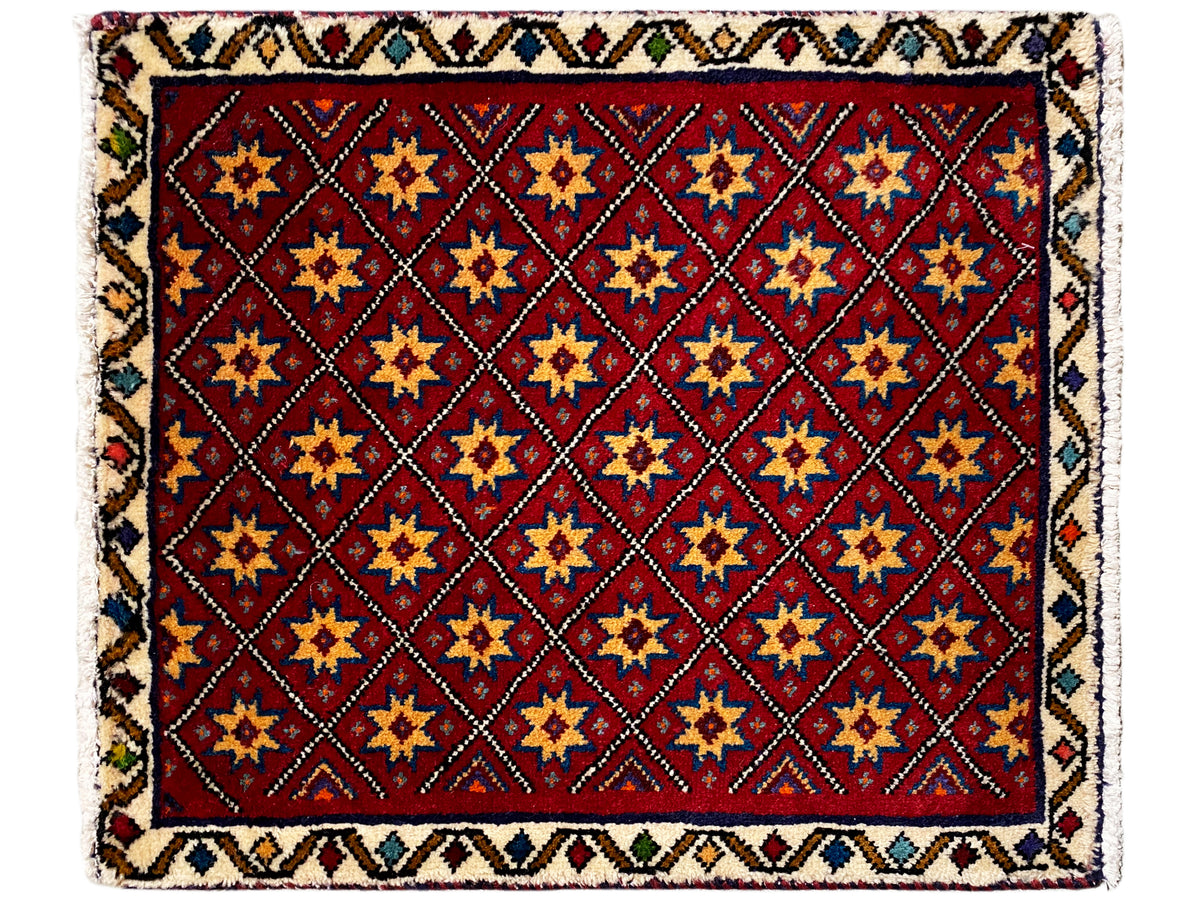 Square rug with a red motif and a multicolored geometric tiled star pattern