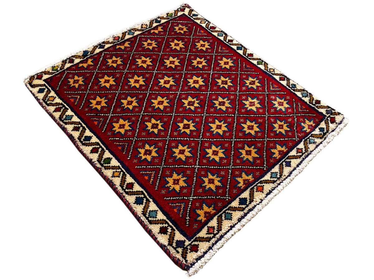 Square rug laid out with a red geometric pattern and colorful border