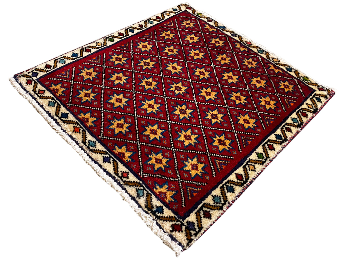 Square rug diagonally patterned with a red background and multicolored star squares